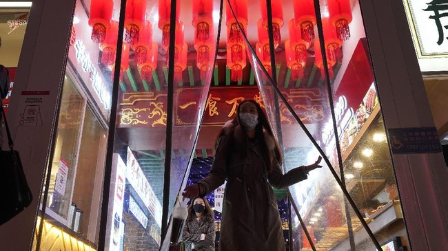 PurnaWarta - Seorang wanita yang mengenakan masker terlihat meninggalkan tempat makan di kota Wuhan, provinsi Hubei, China, pada Kamis (14/1). (AP Photo/Ng Han Guan)