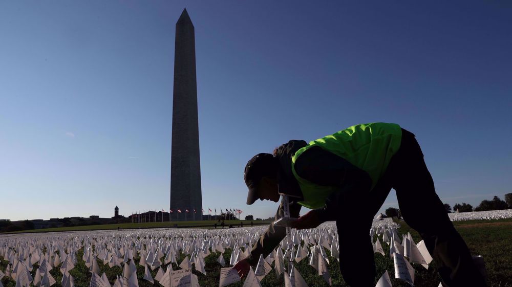 Relawan Sarah Wagner menaruh bendera geolocating sebagai bagian dari “In America: Remember” di sebelah Monumen Washington di Washington, AS, 1 Oktober 2021, karya Suzanne Brennan Firstenberg, sebuah peringatan untuk orang Amerika yang meninggal karena penyakit COVID-19 ketika jumlah kematian di negara tersebut mendekati 700.000.