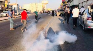 Para pengunjuk rasa menghindari tabung gas air mata di sebuah jalan di Sitra, Bahrain pada 1 Oktober 2021.